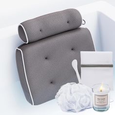 a white bath tub next to a candle and tissue