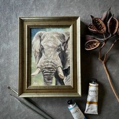 an elephant is shown next to some paint and other items on the table with it's frame