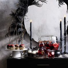 an assortment of desserts and drinks on a table with candles in front of a mirror