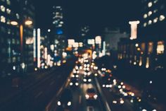 a city street filled with lots of traffic and tall buildings in the background at night