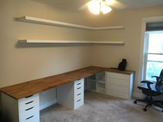 a room with a desk, chair and shelves in the corner next to a window