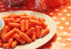 carrots on a white plate next to a small bowl of dip and candy canes