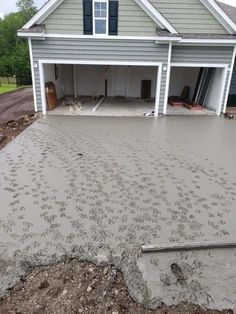 a house that is being built with concrete in front of it and the garage door open