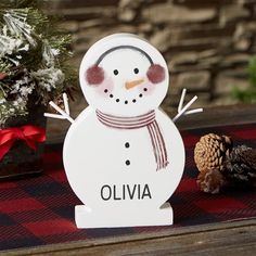 a wooden snowman standing next to a pine cone