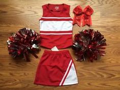 cheerleader uniform and pom poms on wooden floor with red ribbon bow in background