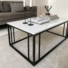 a coffee table with candles and books on it in front of a gray couches