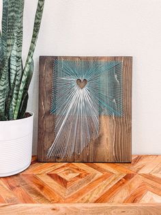 a potted plant sitting on top of a wooden table next to a framed painting