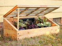 a wooden box filled with plants sitting on top of the grass next to a building