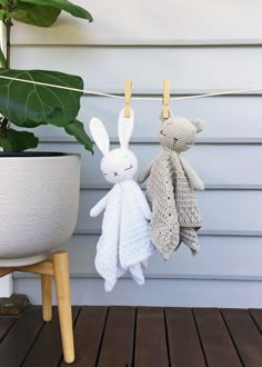 two knitted rabbits hanging on clothesline next to potted plant