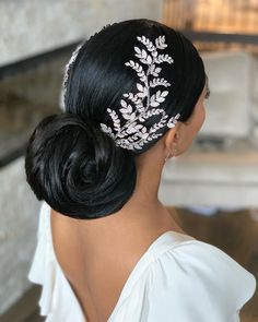 a woman in a white dress wearing a hair comb with silver leaves on it's side