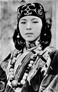 an old black and white photo of a woman in native dress with beads on her head