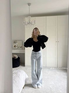 a woman is taking a selfie in her bedroom wearing high waist jeans and a black top