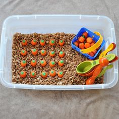 a plastic container filled with cereal and carrots on top of a table next to utensils