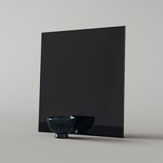 a black bowl sitting on top of a table next to a square wall mounted mirror