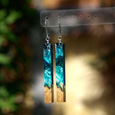 the earrings are made with wood and glass in shades of blue, yellow and brown