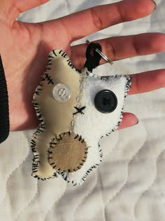 a hand is holding a keychain made out of fabric with buttons on it