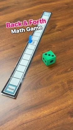 the back and forth math game is next to a green dice on a wooden table