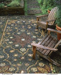 an image of a garden with wooden chairs and graveled area in the middle, surrounded by plants