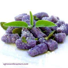 a white plate topped with purple food covered in sugar and sprinkled with green leaves