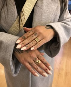 a woman with tattoos on her hands holding onto another person's hand and wearing a coat