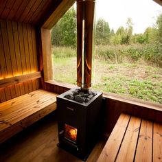 a wood burning stove sitting in the corner of a room with wooden floors and walls