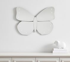 a white butterfly shaped mirror sitting on top of a dresser