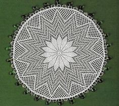 a crocheted doily is shown on a green tablecloth with black beads