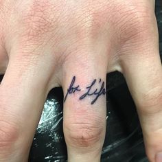 a person's hand with a small tattoo on the middle finger that says love