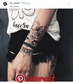 a woman's arm with a flower tattoo on her left wrist and black lace