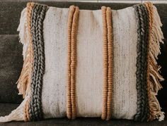 a close up of a pillow on a couch with some beads hanging from the side