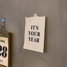 a piece of paper that reads it's your year hanging on the wall next to a clock