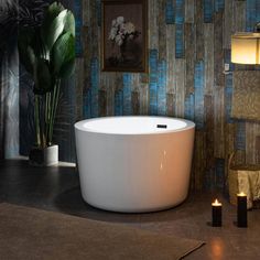 a bath tub sitting on top of a bathroom floor next to a potted plant