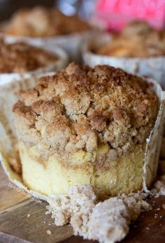 a piece of cake sitting on top of a wooden table next to muffins