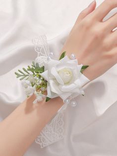 a close up of a person's hand wearing a white wrist corsage