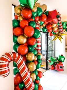 a large christmas tree made out of balloons and candy canes in front of a door