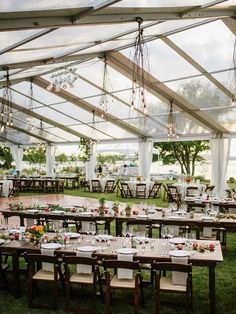 an outdoor tent with tables and chairs set up in the grass for a wedding reception