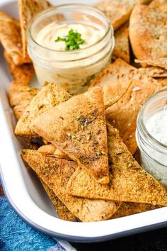 a white platter filled with crackers and dips on top of a blue towel