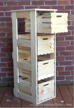 a tall wooden shelf with drawers on it's sides next to a brick wall