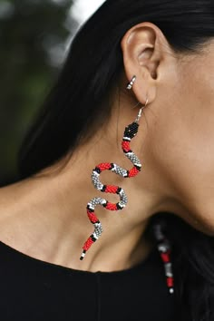 a woman wearing red, white and black snake earrings