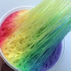 a person is holding a cup with some colored hair on it's side and the inside of their hand