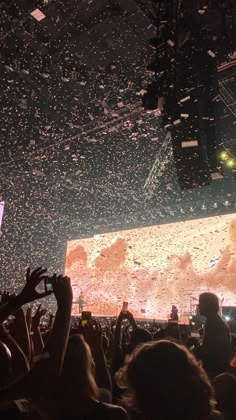 a large screen is in the middle of a concert with confetti falling from it