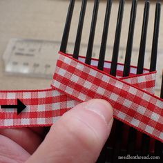 a hand holding a red and white checkered ribbon with an arrow pointing to it