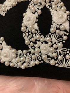 a close up of a black and white purse with pearls on the front, attached to a furnishing