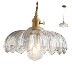 two lights hanging from the ceiling with clear glass shades on each light fixture and one is gold