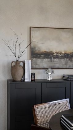 a table with books and vases on top of it next to a black cabinet