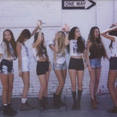 a group of young women standing next to each other in front of a brick wall