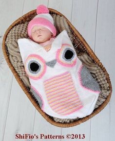 an image of a baby in a knitted owl hat and diaper on top of a basket