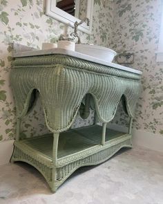 a bathroom with a sink and green wicker cabinet