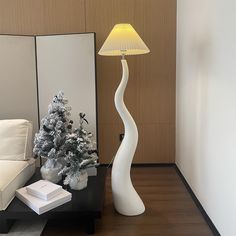 a white lamp sitting on top of a table next to a christmas tree in a living room