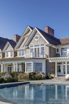 a large house with a pool in front of it and lots of windows on the side